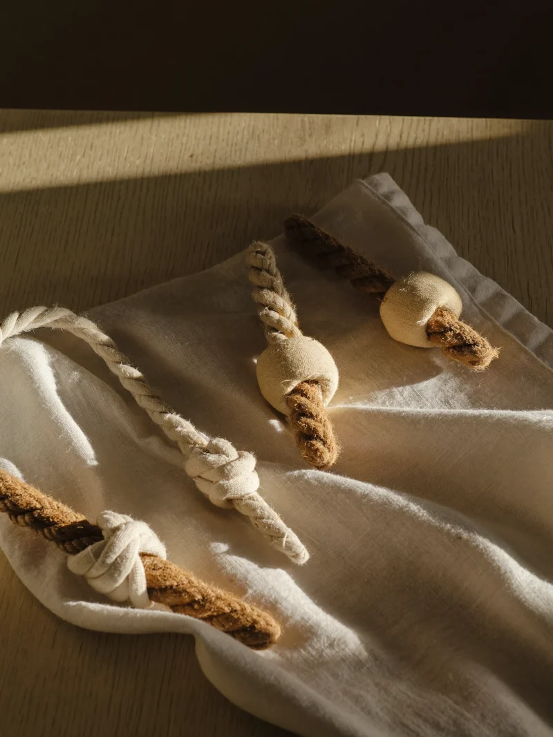 Jouets en toile et corde cousus main disposés sur un lin